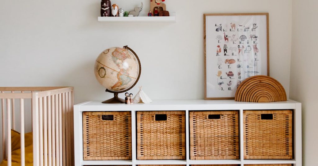 Comfortable bed with toys globe and paintings placed on wooden cabinet with wicker boxes and soft white rug with toy house on floor